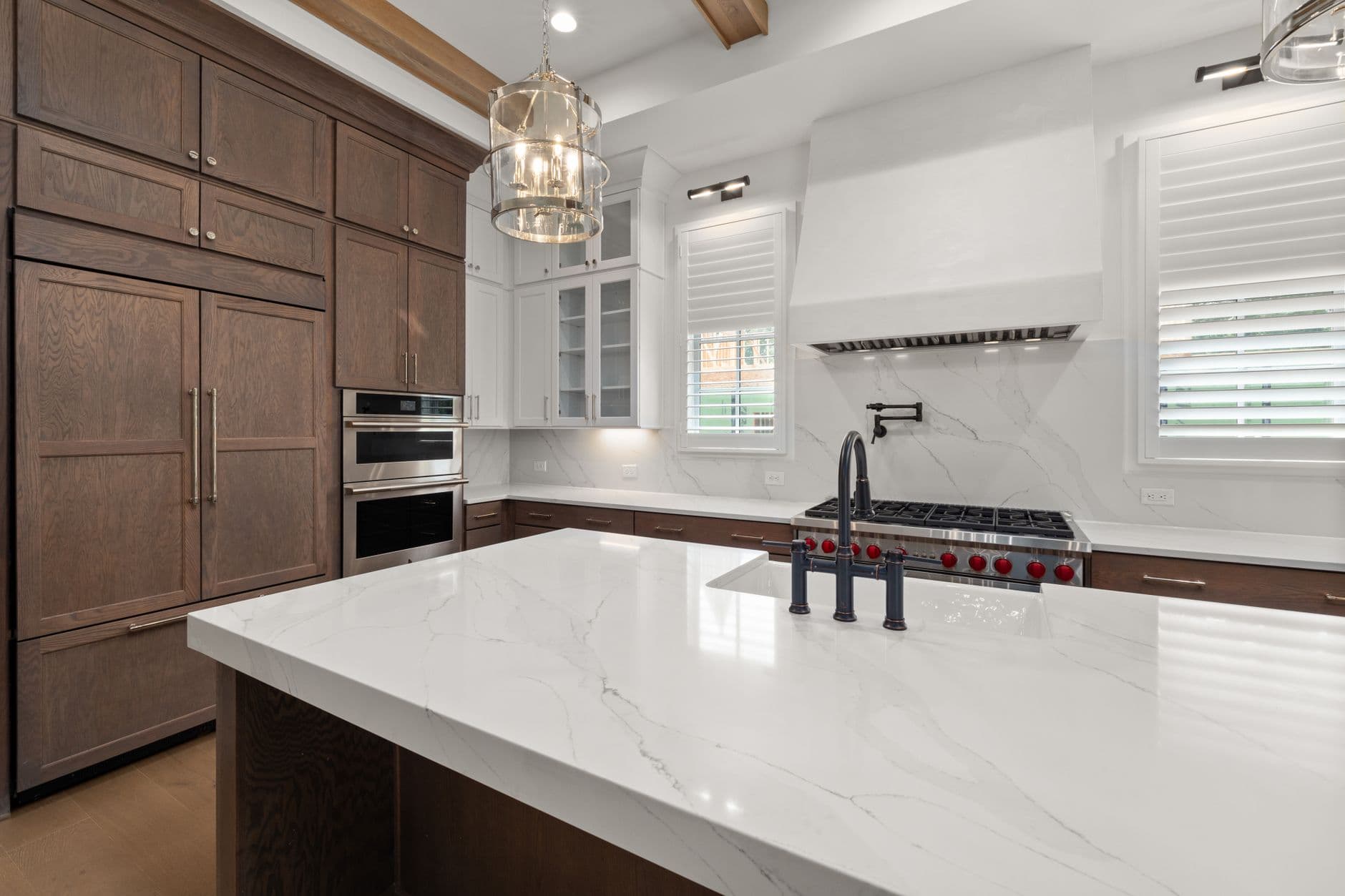Elegant kitchen featuring a marble island, wooden cabinetry, and stainless steel appliances.