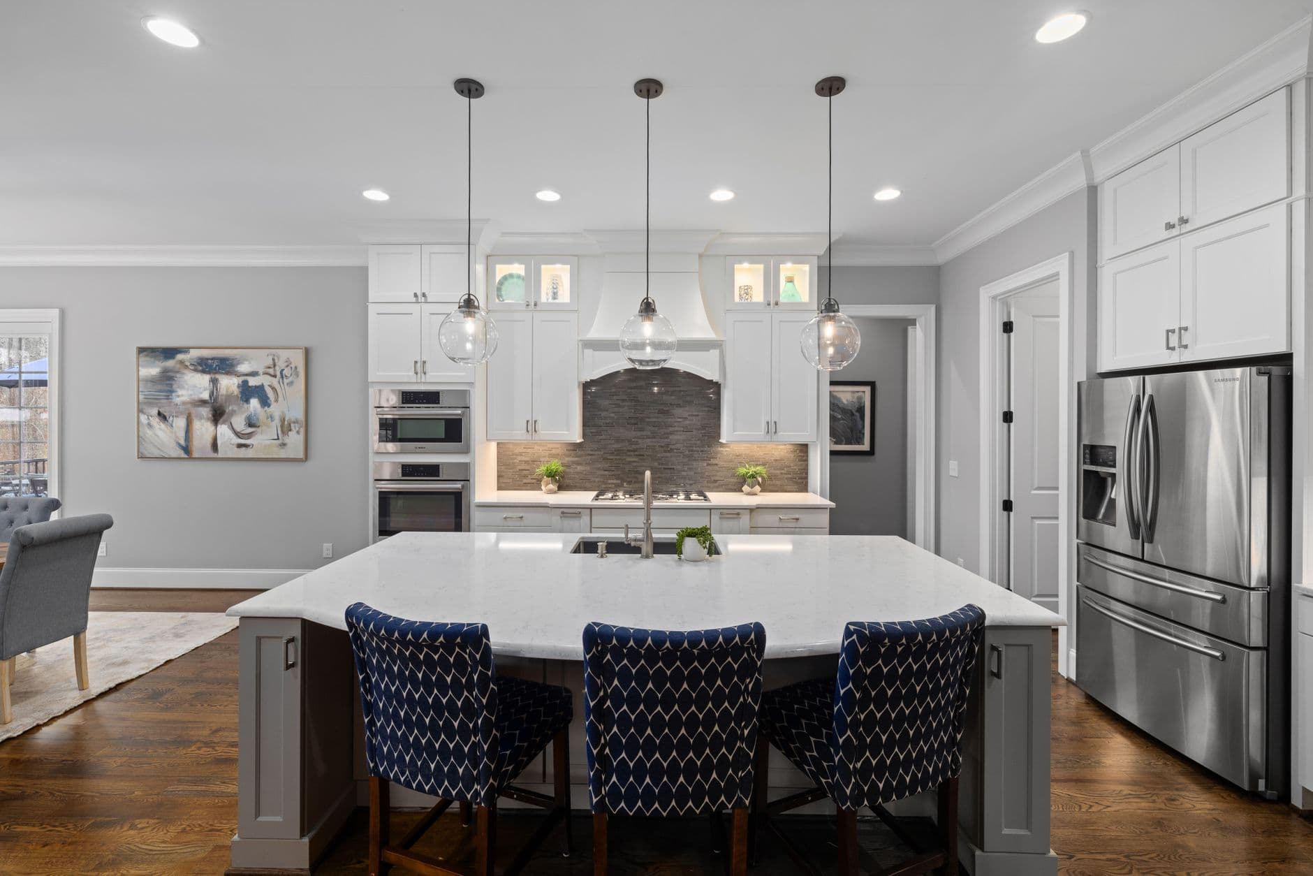Bright modern kitchen featuring white cabinets, island, and stainless steel appliances.